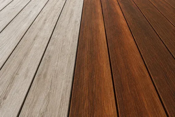 A coastal timber deck part-restored — rich oiled boards beside greyed weathered timber