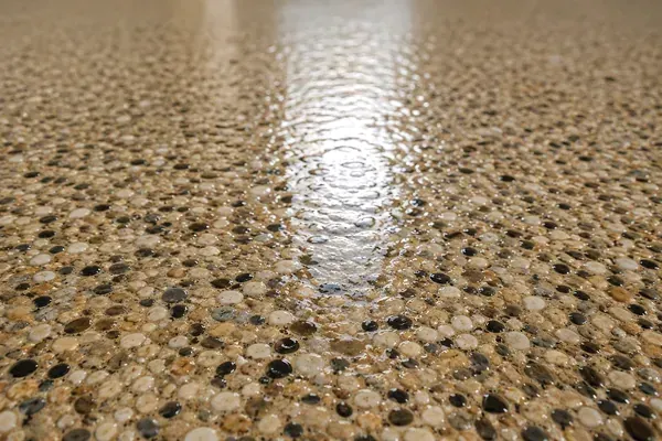 Freshly cleaned and sealed exposed-aggregate driveway with a wet-look sheen at a coastal WA home