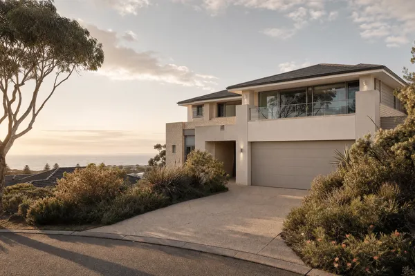 Two-storey home with an ocean glimpse over rooftops on an elevated Warnbro street